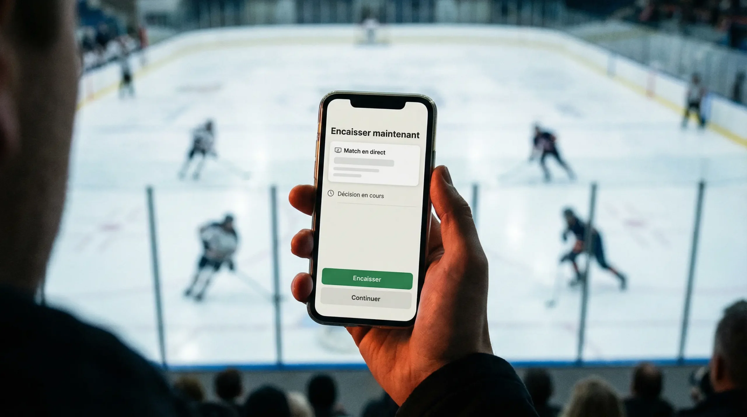 Main d'un spectateur tenant un smartphone lors d'un match de hockey sur glace en direct