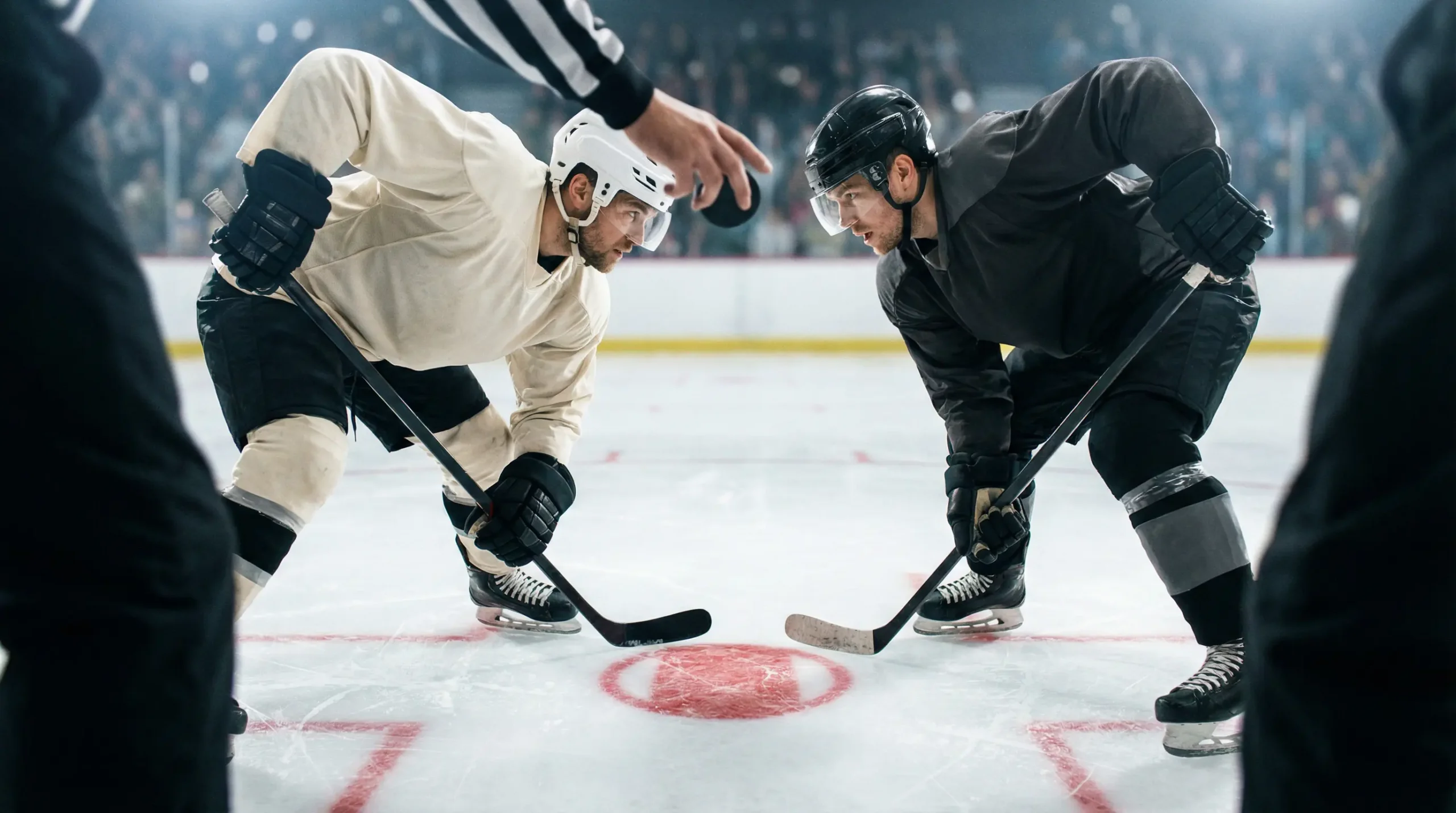 Deux joueurs de hockey face à face lors d'une mise en jeu au centre de la patinoire